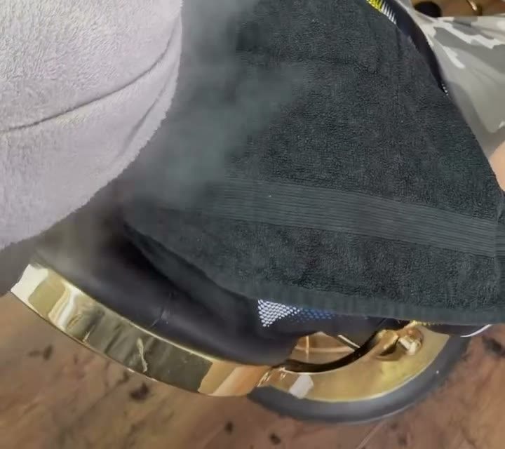 A hot towel over a customer's face under a steamer at La Cave